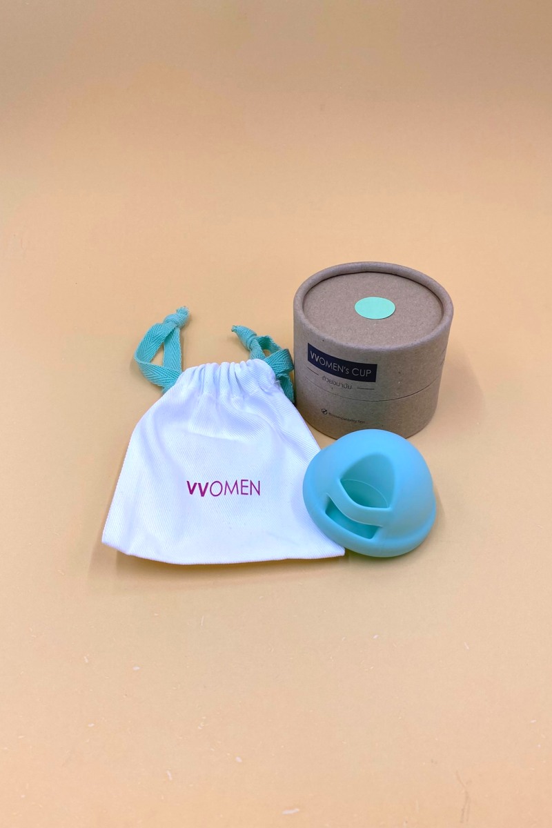 Blue silicone disc with a white bag labeled 'vvomen ' on a beige background.