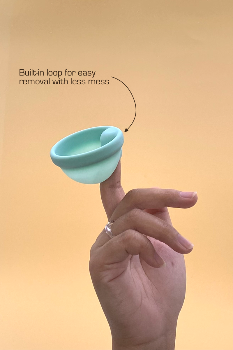 Turquoise menstrual disc by vvomen held by a hand with text on a beige background